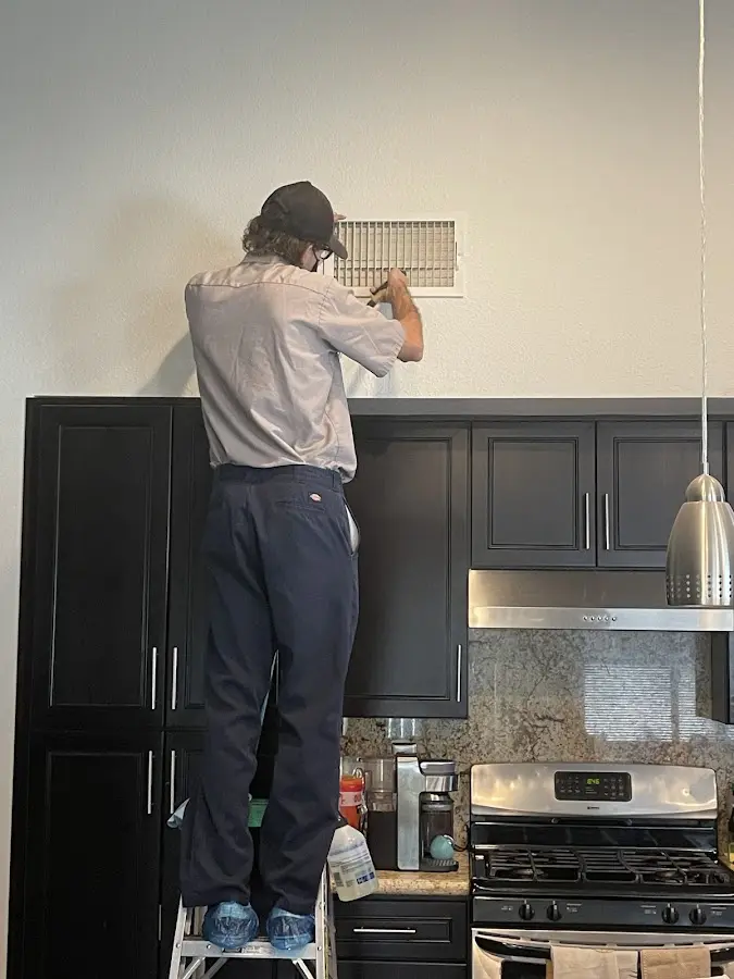 Technician inspecting an air vent during HVAC service in Des Moines